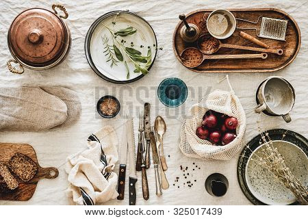 Various Kitchen Utensils, Tablewear And Fresh Bread Over Linen Tablecloth