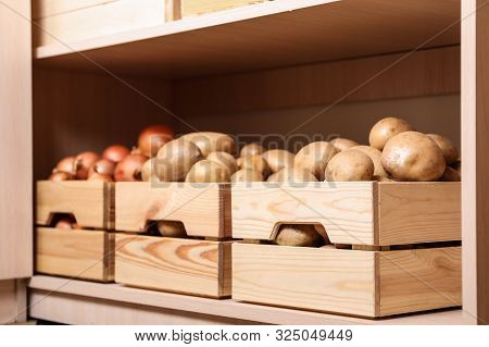 Crates With Potatoes And Onions On Shelf. Orderly Storage