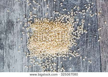 White Sesame Seeds Scattered On The Gray Wooden Surface Of Tabletop