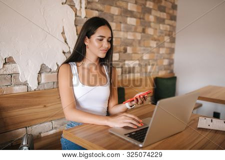 Attractive Smart Girl Working On Laptop In Cafe. Beautiful Girl Using Computer For Work. Girl Grinki