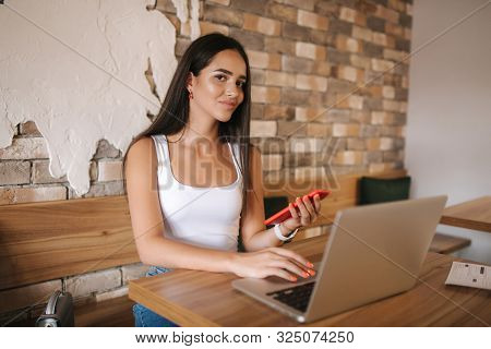 Attractive Smart Girl Working On Laptop In Cafe. Beautiful Girl Using Computer For Work. Girl Grinki