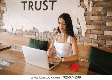 Attractive Smart Girl Working On Laptop In Cafe. Beautiful Girl Using Computer For Work. Girl Grinki