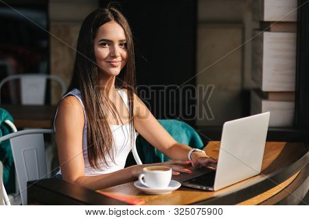 Young Business Lady Work In Laptop And Dring A Coffee. Beautiful Girl Sitting In The Cafe Outside Wo