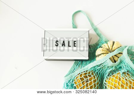 Autumn Flat Lay Composition With White, Orange Pumpkins In Blue Mesh Shopping Bag On White Backgroun