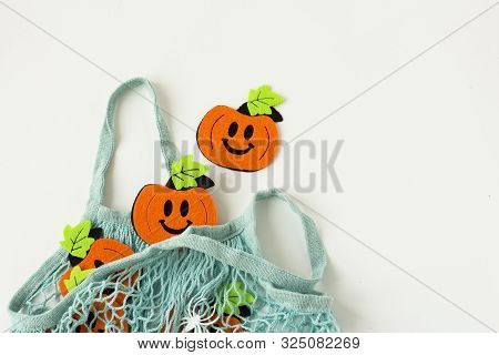 Autumn Flat Lay Composition With Orange Felt Pumpkins In Mesh Shopping Bag On White Background. Crea