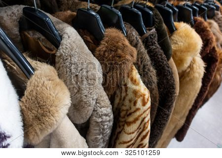 Rail of secondhand fur coats for sale in a thrift store or charity shop 