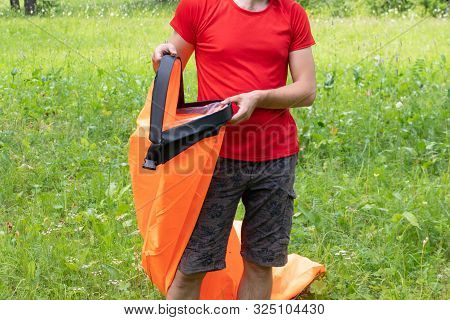 Man Unpacks Inflatable Sofa In The Park. Man Tries To Inflate An Air Sofa