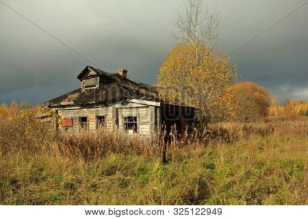 Autumn Landscape With An Old Ruined Wooden House. Old House In A Field In The Village On A Sunny Day