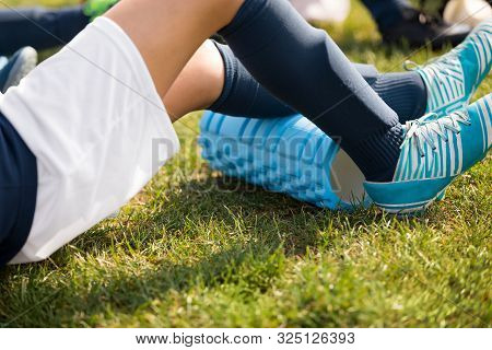 Young Athlete Boy Using Foam Roller On Sports Training. Soccer Player On Warm-up Cooldown After Outd