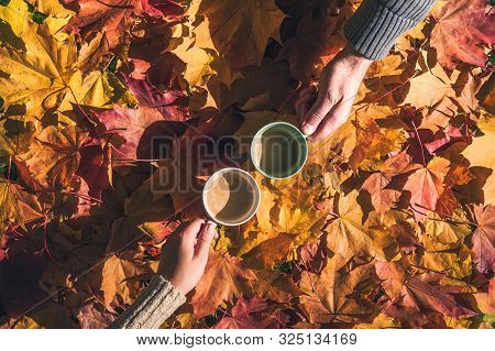 Cuple Of Man And Woman With Two Cup Of Coffee On The Ground With Maple Leaves In The Autumn Forest. 