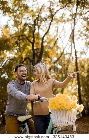 Active Young Couple Enjoying Together In Riding Bicycle In Golden Autumn Park
