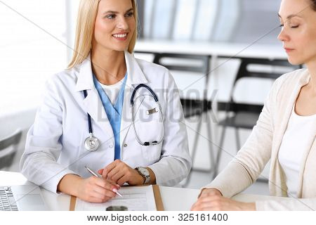 Doctor Woman At Work In Hospital Excited And Happy Of Consulting Female Patient. Blonde Physician Co
