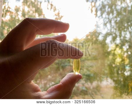 Vitamin D Is Healthy When There Is No Sun. Yellow Soft Shell Vitamin Capsule Against The Blue Sky On