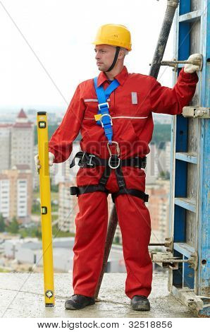 worker mounter with level and concrete formwork at construction site roof