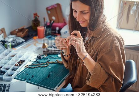 Happy Smiling Woman Is Working On Beads Jewellery At Her Own Workplace.