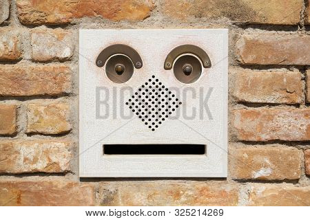 A Funny Doorbell Panel On Old Brick Wall And Mail Post Box With Letter. Fake Face Concept