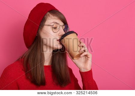 Studio Shot Of Beautiful Woman Dresses Red Shirt, Spectacles And Beret, Holding Cup Of Coffee In Pla