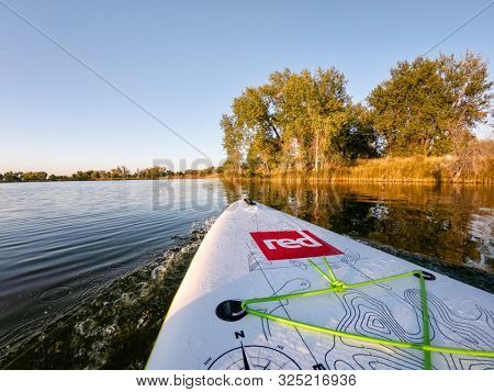 Fort Collins, CO, USA - September 26, 2019: Bow of inflatable stand up paddleboard by Red Paddle Co on calm lake in Colorado in fall scenery, POV by action camera.