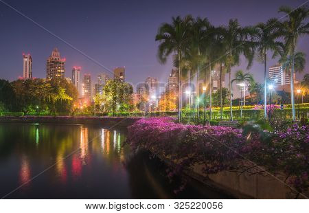 Lake With Calm Water Reflecting Nearby Buildings In South Part Of Benjakiti Public Park At Night In 