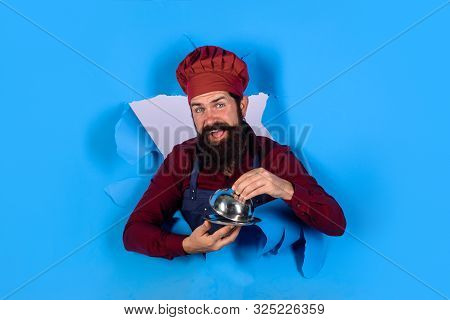 Cook Man With Cloche Through Paper. Professional Chef Holds Dish. Chef With Metal Cloche. Waiter Hol