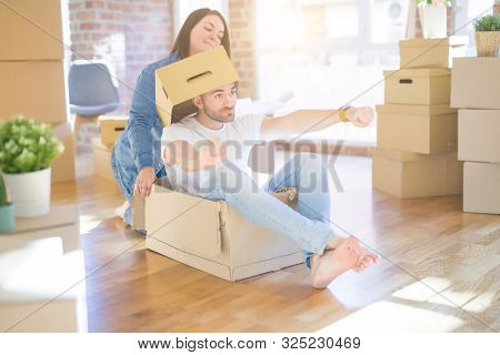 Funny and crazy couple having fun riding a cardboad box as a car, smiling happy and lauging at new home