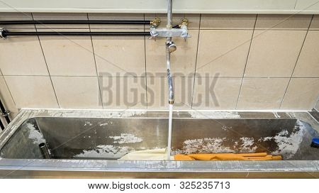 On The Wall There Is A Running Kitchen Faucet In A Laundry Room