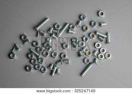 Metal Bolts And Nuts In A Gray Background. Chromed Screw Bolts And Nuts. Set Of Nuts And Bolts