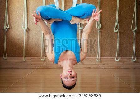 Portrait Of A Beautiful Young Woman Engaged In Anti-gravity Yoga On Canvases In A Lotus Pose. Yoga O