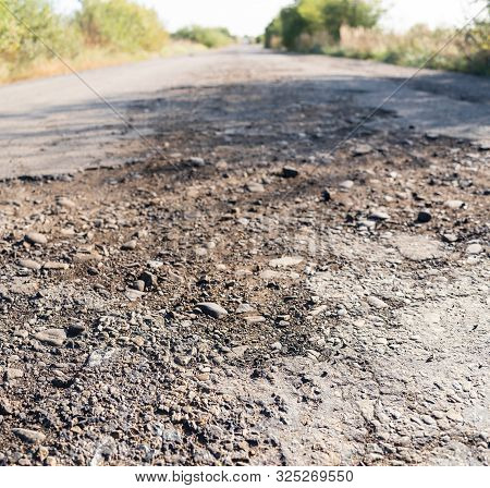 Destroyed Asphalt Cover On Road. Bad Road Condition That Needs Repair. Theme Of Road Construction An