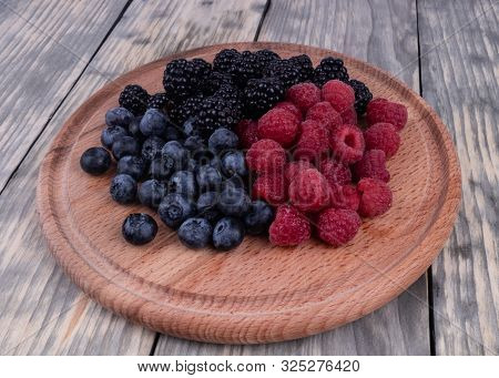 Side View On Wooden Plate With Sumer Red, Blue And Blackberries Textured Wooden Background