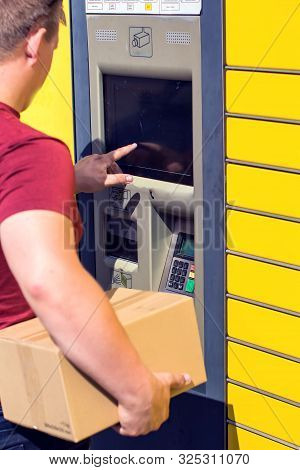 Man Client Using Automated Self-service Post Terminal Machine Or Locker To Depisit A Parcel For Stor