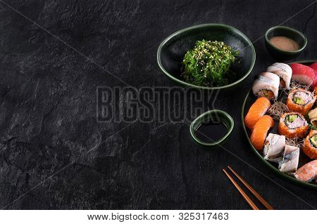 Assorted Sushi Set Served On Dark Stone Slate Background. Seaweed Wakame Salad, Seafood, Various Mak