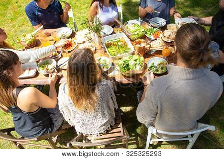 Young Friends At Table Outdoor. High Angle View Of Male And Female Friends Gathering Around Table Wi