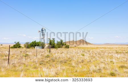 Windmill On A Farm In Rural Grassland Area Of South Africa