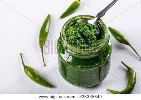 Hot Chili Pepper Paste. Green Sauce In Glass Jar On White Background. Adjika Or Ajika In Georgian Cu