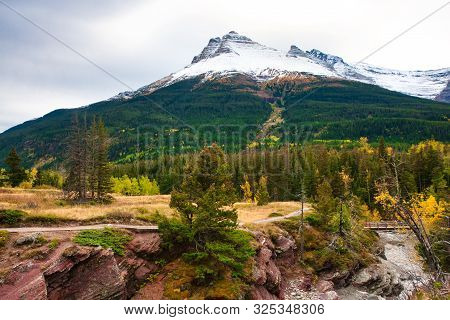 View Of The Snowy Mountain Peak In Waterton Lakes National Park From The Bridge Across The River On 