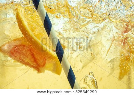Close Up Of Lemon Slices In Stirring The Lemonade And Ice Cubes On Background. Texture Of Cooling Sw