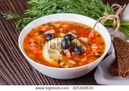 Traditional Russian Meat Soup Solyanka In Bowl On Rustic Wooden Table