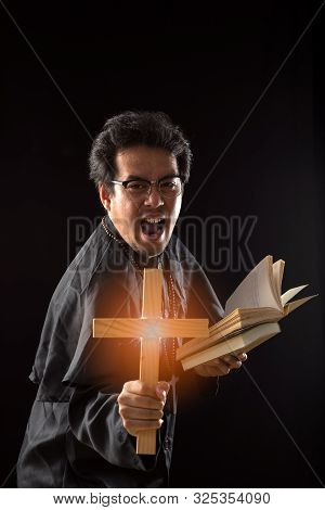 Dark Tone, Rim Light - Priest Show Crucifix While Holding Bible  To Exorcise Ghost On Black Backgrou