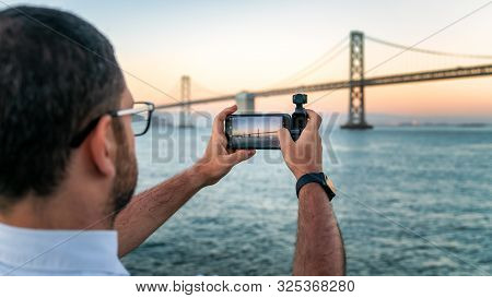 Usa, San Francisco - August 2019: A Photographer Is Using Osmo Pocket To Take Footage Of A Lake.