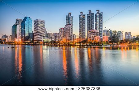 Lake In City Park Under Skyscrapers At Twilight. Benjakiti Park In Bangkok, Thailand