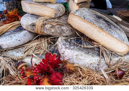 Close-up view of semi-hard cheese wrapped in straw on the stall at the market in Italy.
