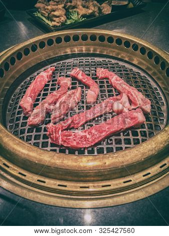 Japanese BBQ restaurant barbecue grill top view of table grilling yakiniku of raw steak meat premium cuts. Japan culture dining experience cooking.