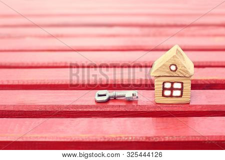 Small Wooden Hut And Key On A Red Surface Front View. Retro Real Estate