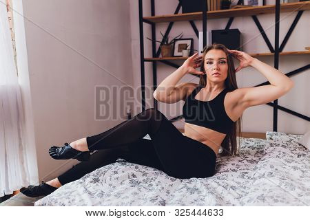 Attrctive Fitness Woman Doing Stretching Exercises At Home, As Part Of A Healthy Lifestyle Without G