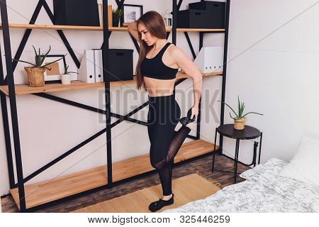Attrctive Fitness Woman Doing Stretching Exercises At Home, As Part Of A Healthy Lifestyle Without G