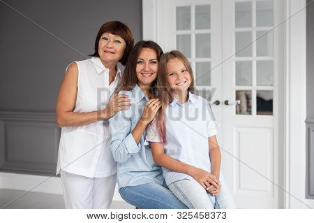 Daughter, Mother And Grandmother Stand Closeto Each Other And Hugging