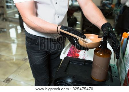Male Stylist In Gloves Preparing Color Cream For Dying Hair Container, A Mask For Treatment Procedur