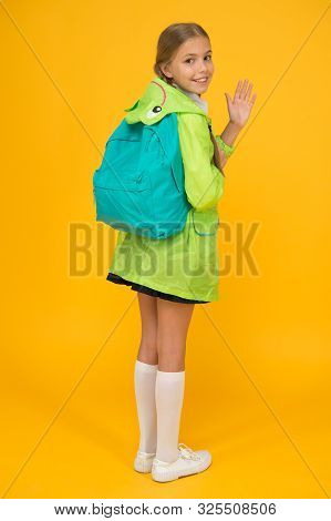 Rain Is Not Hindrance. Schoolgirl Raincoat Going To School Waving Hand. Waterproof Fabric For Your C