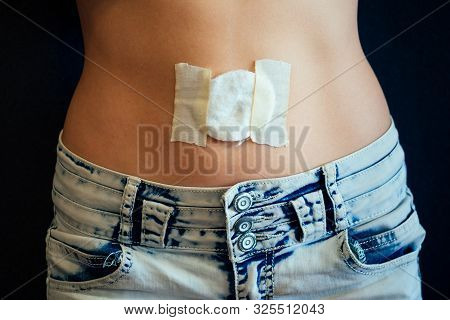 Belly Of A Young Woman With A Bandage And Cotton On Her Stomach. Care Navel Ring Piercing Concept